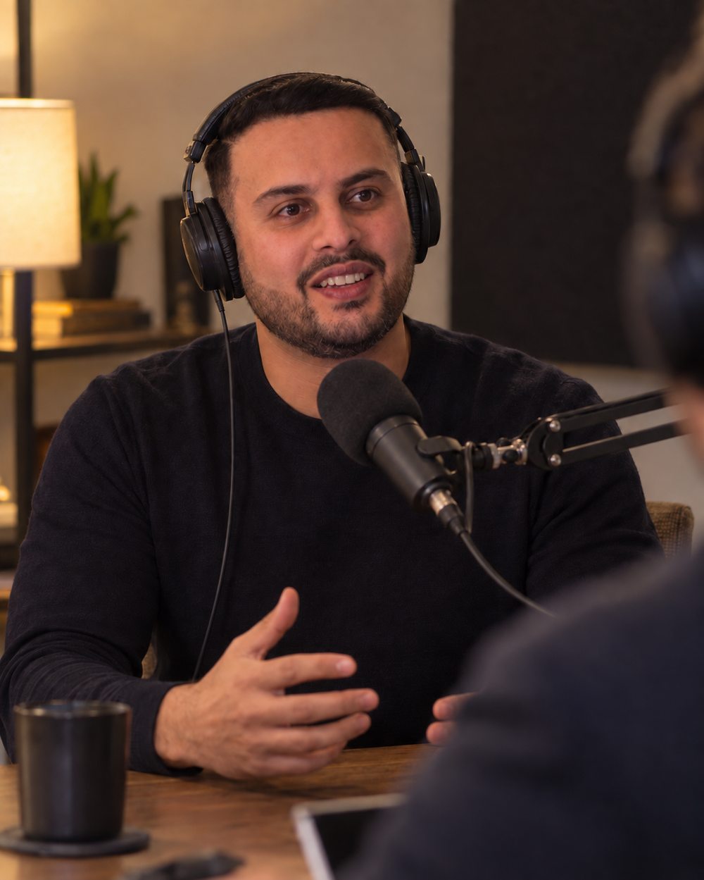 Dil Phagura speaking into a studio microphone while recording an interview.